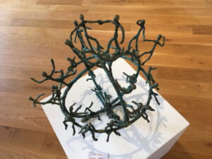 Kunstobjekt auf schwarzem Metall, das eine stilisierte Weltkugel mit miteinander verbundenen Strichfiguren darstellt.