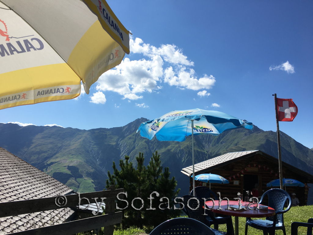 Alp Bischola-Bergrestaurant: Sonnenschirme unter Blauhimmel in Bergumgebung