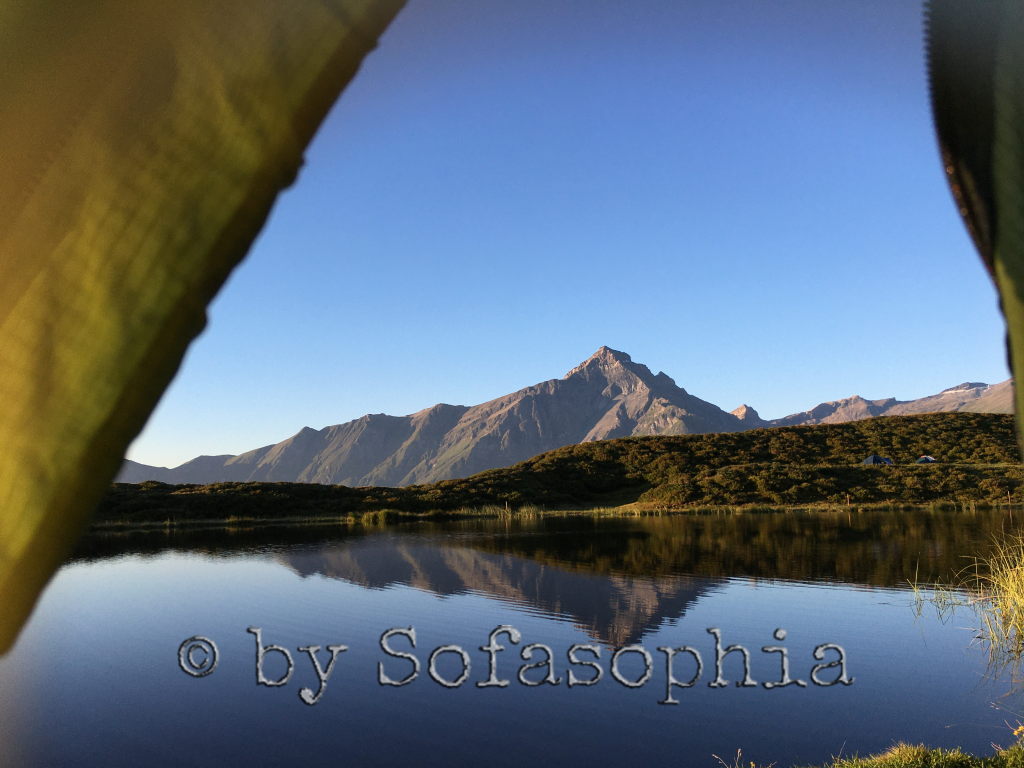 Blick aus dem Zelt auf den See und das Bergmassiv dahinter. Spiegelungen im See.