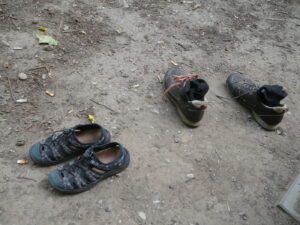 Zwei Paar Schuhe auf dem erdigen Boden.
