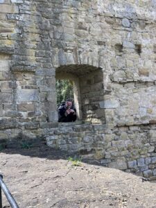 Fensteröffnung in Steinmauer, aus der ein Mann herausschaut und fotografiert