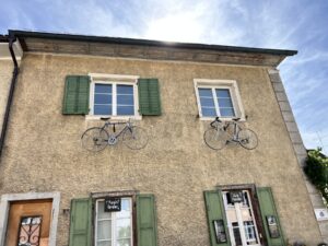 hellbraune Hausfassade, an welcher bei den zwei oberen Fenstern zwei Fahrräder aufgehängt worden sind