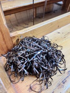 Ein Knäuel Bandsalat aus einer alten Tonbandkassette auf einer Holzbank liegend, Nahaufnahme