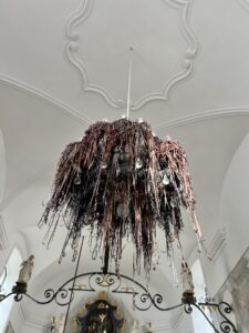 Bandsalat von alten Kassetten um den Kronleuchter in der Kirche gewickelt als Kunstobjekt, darüber Stuckdecke